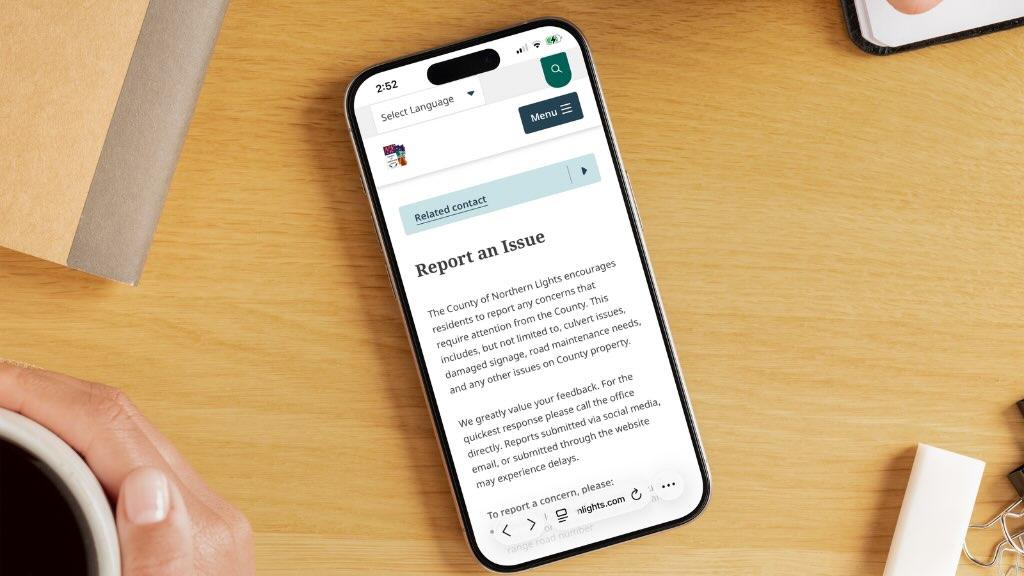an iPhone laying on a table, the screen displays the County report an issue webpage